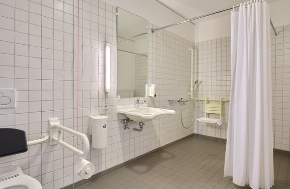 rollstuhlgerechtes Bad mit unterfahrbarem Waschbecken, ebenerdiger Dusche und Haltegriffen