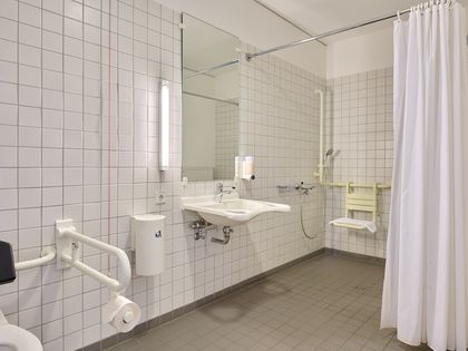 rollstuhlgerechtes Bad mit unterfahrbarem Waschbecken, ebenerdiger Dusche und Haltegriffen